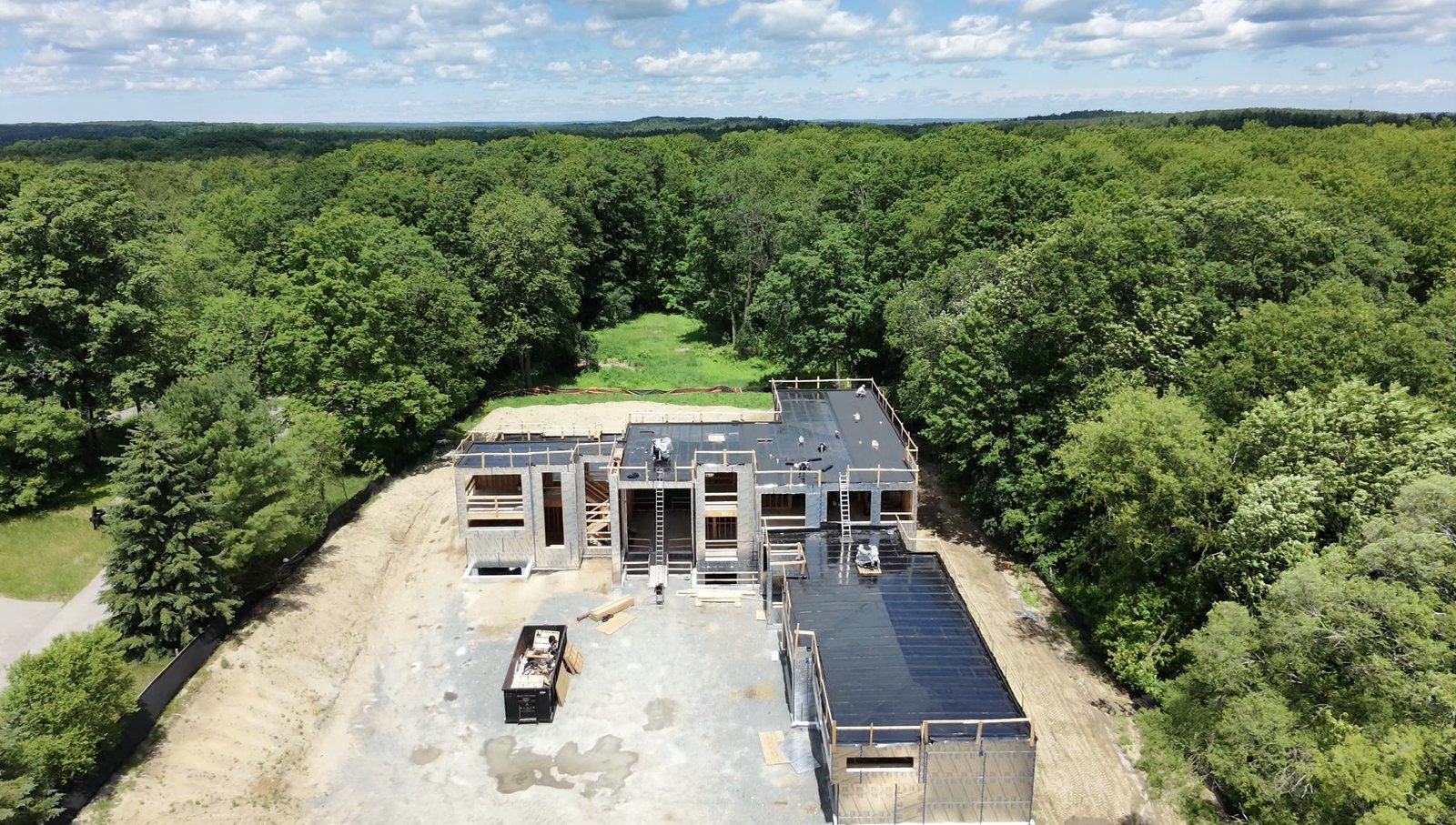 Aerial view of a new custom home in Stouffville with a 2-ply flat roof being installed by Spiros Aluminum & Roofing